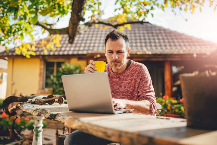 man in tuin achter pc